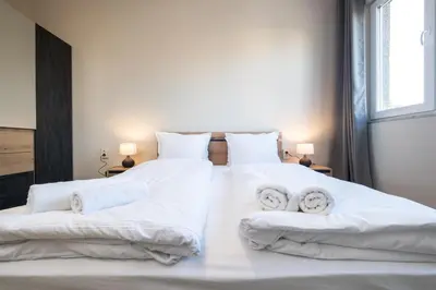 two beds with white sheets and towels on them at Panoramic View Cozy 1BR Apartment in Plovdiv
