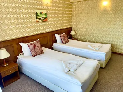 a hotel room with two beds and a table at Хотел Елит Релакс in Devin