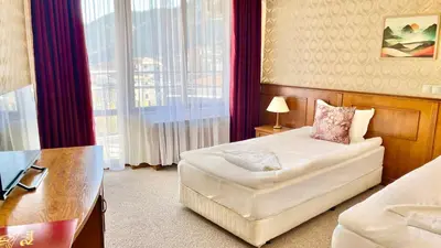a hotel room with a bed and a desk and a window at Хотел Елит Релакс in Devin