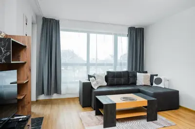 a living room with a black couch and a table at Modern Stay with Balcony in Sofia