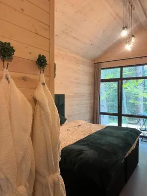 a bedroom with a bed in a room with wooden walls at Zarevo Glamping Forest Houses in Skobelevo