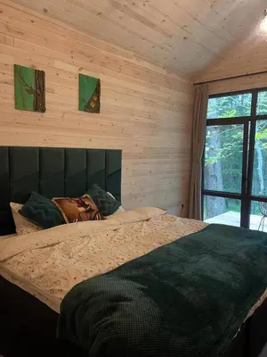 a bedroom with a large bed in a wooden wall at Zarevo Glamping Forest Houses in Skobelevo