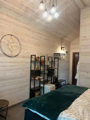 a bedroom with wooden walls with a bed and shelves at Zarevo Glamping Forest Houses in Skobelevo