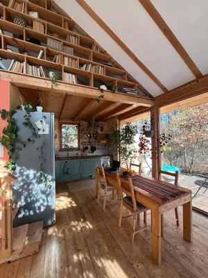 a kitchen and dining room with a table and a refrigerator at Cozy frame house in the wood