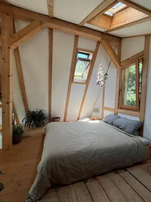 a bedroom with a large bed in a room with wooden ceilings at Cozy frame house in the wood