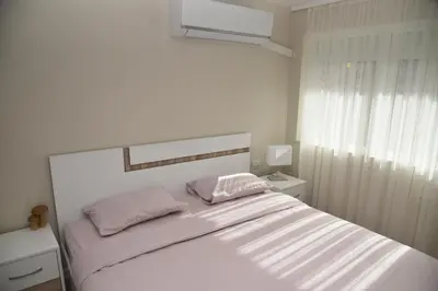 a white bedroom with a bed with two pink pillows at C&A Apartment in Gotse Delchev