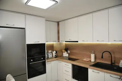 a kitchen with white cabinets and a black appliance at C&A Apartment in Gotse Delchev