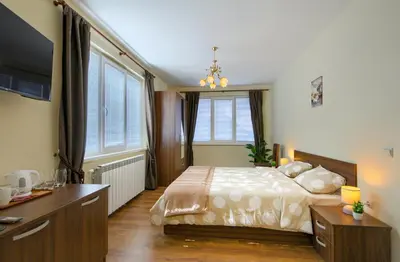 a bedroom with a bed and a desk and windows at Rila North Samokov in Samokov