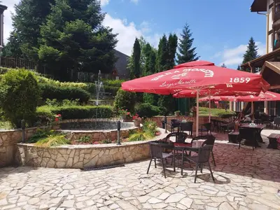 a patio with tables and chairs with an umbrella and a fountain at Alpin Art Studio in Hotel Iceberg - Free Pool, Sauna and Fitness in Borovets