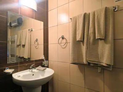 a bathroom with a sink and a mirror and towels at Urban Atelier 300m from Gondola, Free Bottle of Wine, free Parking in Bansko