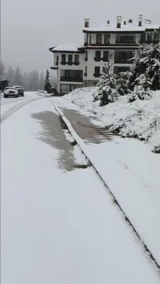 a street covered in snow with a building in the background at Аppartment Dreams in Pamporovo