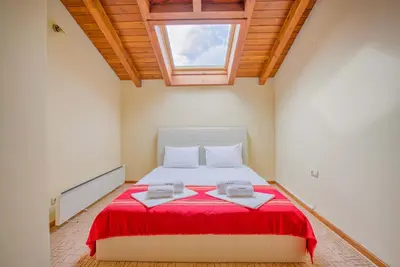 a bedroom with a bed with a red blanket and a window at Stylish Two-Level Apartment in Bansko by Flat Mаnаger in Blagoevgrad