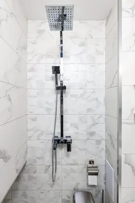 a shower in a bathroom with white marble walls at Top-Floor Flat with Balcony by Flat Manаger in Plovdiv
