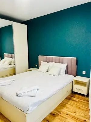 a bedroom with a large bed with a blue wall at Urban Glow Apartment near Metro Station in Sofia