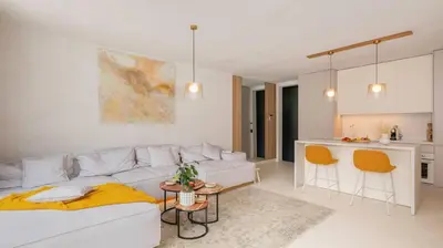 a living room with a white couch and a kitchen at Unique Designer Retreat | Mins to Gondola - Patio! in Bansko