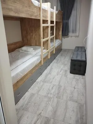 a bedroom with two bunk beds and a wooden floor at Странската изба град Калофер in Kalofer