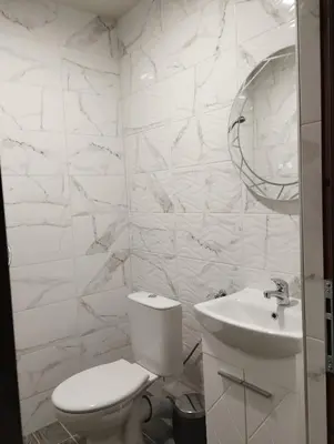 a white bathroom with a toilet and a sink at Странската изба град Калофер in Kalofer