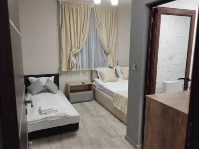 a small bedroom with two beds and a window at Странската изба in Kalofer