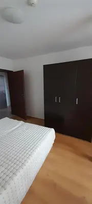 a bedroom with a white bed and black cabinets at Апартамент Kosara 44 in Bansko