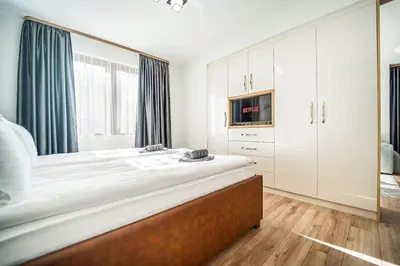 a white bedroom with a large bed and a tv at Best Central Lux Studio in Bansko
