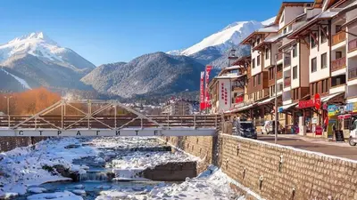 a street in a town with a river and snowy mountains at Best Central Lux Studio in Bansko