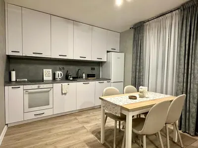 a kitchen with white cabinets and a table and chairs at Casa Nova with Free Garage Parking in Plovdiv