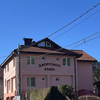 a pink building with a sign on the side of it at Dzhorgovata Guesthouse in Govedartsi
