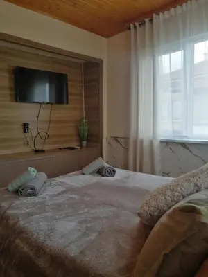 a bedroom with a large bed with a television on the wall at Уют in Haskovo