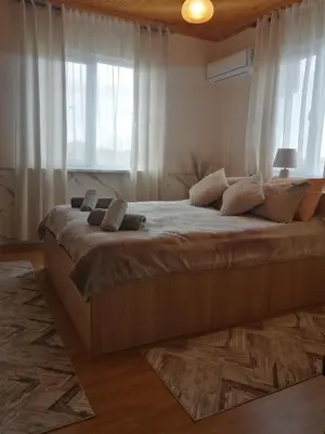 a large bed in a room with windows at Уют in Haskovo