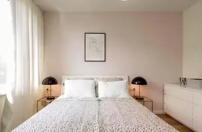 a white bedroom with a bed with two lamps at Mattea's 2-bedroom apartment in Sofia