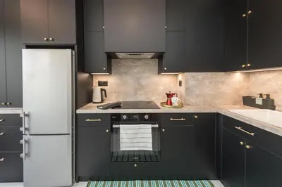 a kitchen with black cabinets and a white refrigerator at Mattea's 2-bedroom apartment in Sofia
