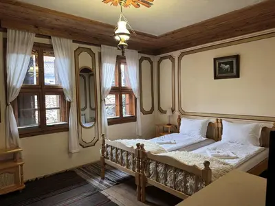 a bedroom with a bed in a room with windows at Мандулова Къща in Koprivshtitsa
