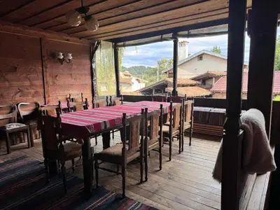 a dining room with a table and chairs on a deck at Мандулова Къща in Koprivshtitsa