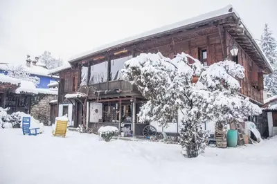 a snow covered house with a tree in front of it at Мандулова Къща in Koprivshtitsa
