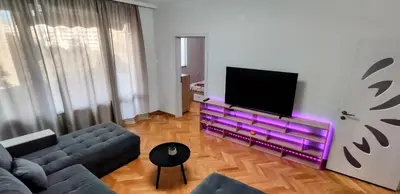 a living room with a tv and purple furniture at violet's dream in Plovdiv