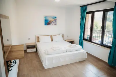 a bedroom with a white bed and a large window at Къща за гости Бели Осъм in Beli Osŭm