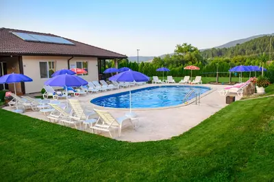 a swimming pool with chairs and umbrellas at Вилен комплекс Дарибел in Sapareva Banya