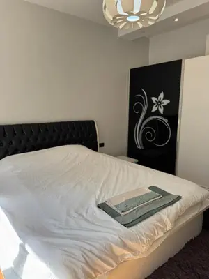 a bedroom with a white bed with a black headboard at Central Elegance NDK 3BDR in Sofia