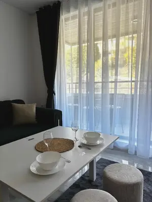 a living room with a table with plates and wine glasses at Thermal Bliss Apartment in Velingrad