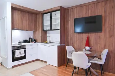 a kitchen with white cabinets and a table with chairs at Apartment Dream - Comfort & Calm in Pirin Sense by Flat Mаnаger in Bansko
