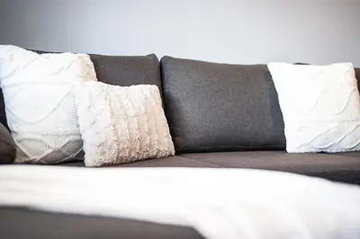 a couch with three pillows on top of it at 400m from Ski Belvedere Apartment - Free Parking - SPA in Bansko