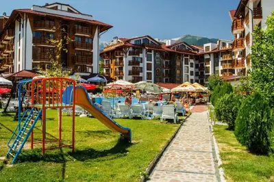 a playground with a slide and chairs and buildings at 400m from Ski Belvedere Apartment - Free Parking - SPA in Bansko