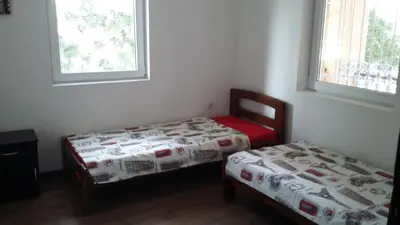 two beds in a room with two windows at Guest House The House in Plovdiv