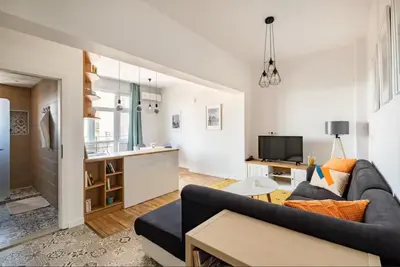 a living room with a couch and a kitchen at Cozy 2BDR Balcony Apt with View in Historic Center in Sofia