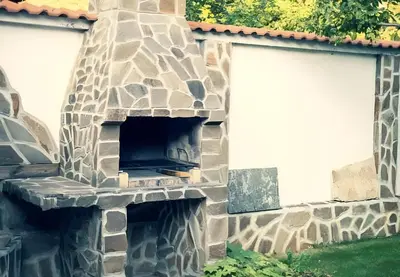 an outdoor pizza oven in the side of a house at Къща за гости Бумеранг in Velingrad