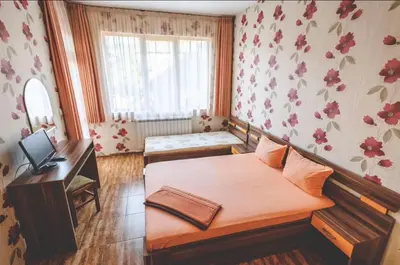 a bedroom with a bed and a desk and a window at Къща за гости Бумеранг in Velingrad