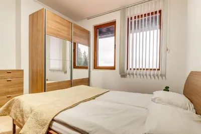 a bedroom with a bed and two windows at Alpine Comfort at Grand Monastery in Pamporovo