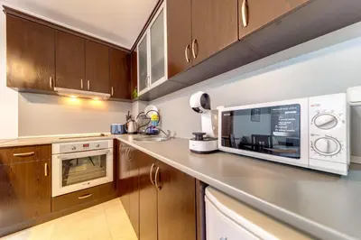 a kitchen with wooden cabinets and a microwave at Slopeview Stay at Grand Monastery in Pamporovo