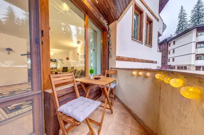 a small balcony with two chairs and a table at Cozy Evrika 2 Mountain Home in Pamporovo