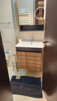 a bathroom with a sink and a mirror and a rug at SPOMAR One Bedroom Apartment in Bansko